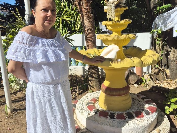 Mãe Dalva de Iemanjá em jardim com fonte de água, ambiente de paz