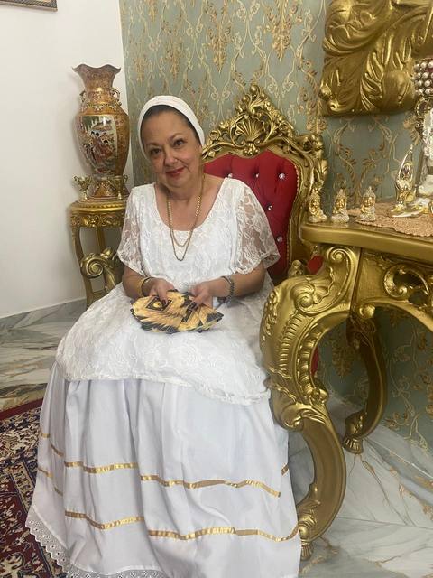 Mãe Dalva em vestido vermelho e dourado, com o baralho de tarot em mãos