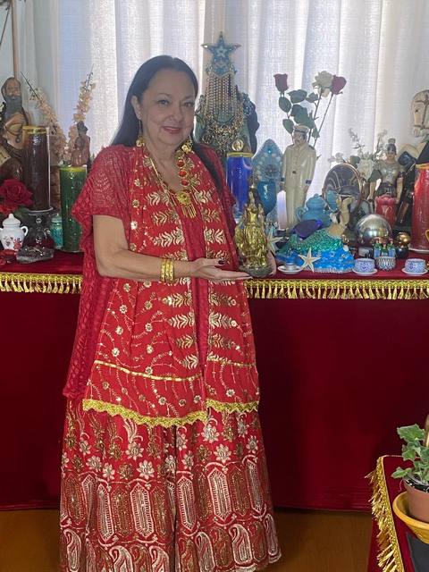 Mãe Dalva junto ao altar, entre velas, rosas e imagens sagradas