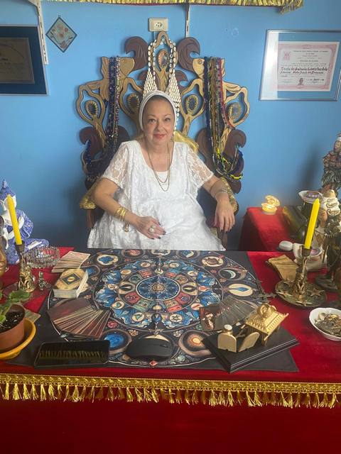 Espaço de atendimento de Mãe Dalva, com mesa de tarot e búzios