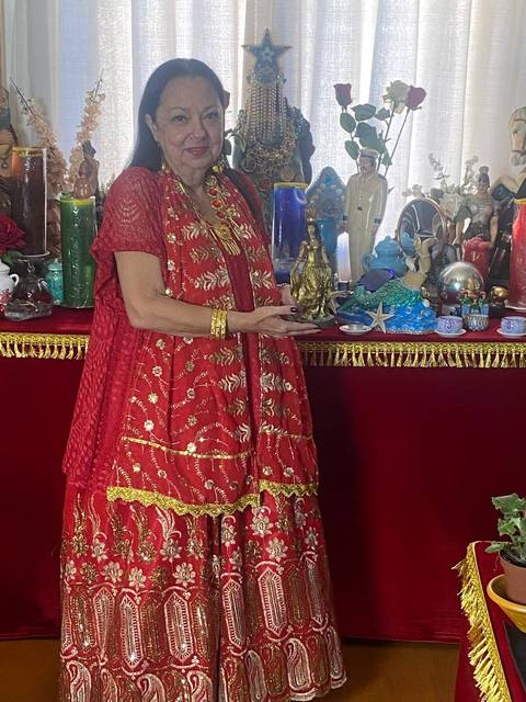 Mãe Dalva no altar, cercada por imagens e flores