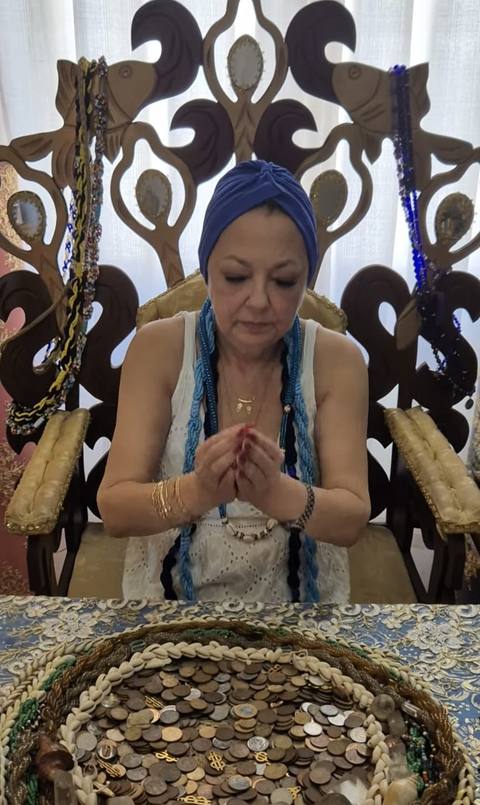 Mãe Dalva em consulta de búzios, com moedas sobre a mesa