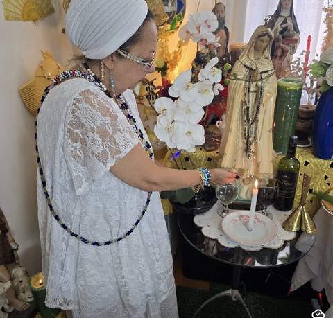 Mãe Dalva acendendo velas no altar espiritual